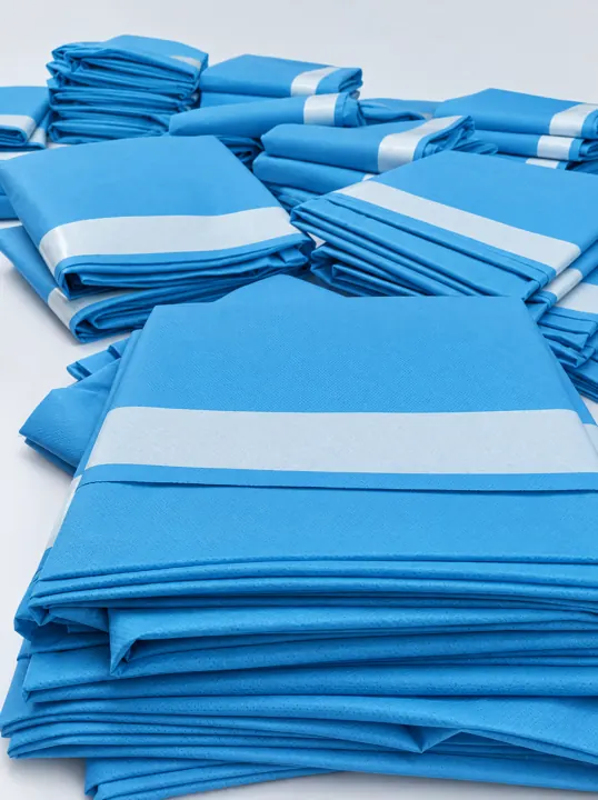 Stack of folded blue surgical drapes with lighter reinforcement bands | OP-Abdecktücher | Teli chirurgici