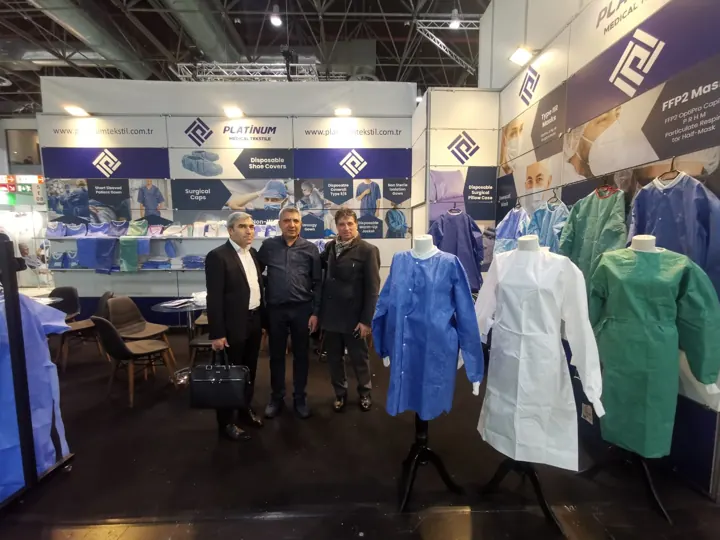 At our trade fair booth with customers in front of sample gowns and coveralls | Mit Kunden an unserem Messestand | Con i clienti al nostro stand in fiera