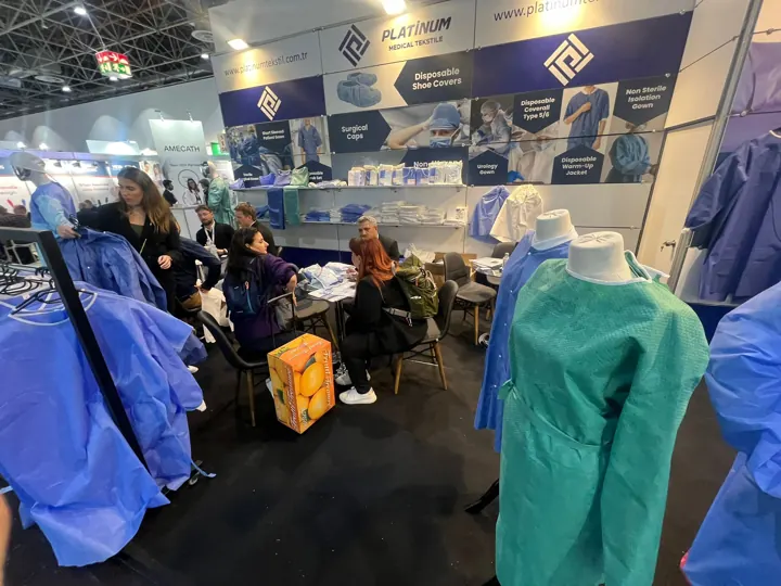 Visitors at the booth with a green gown sample | Besucher am Messestand | Visitatori allo stand